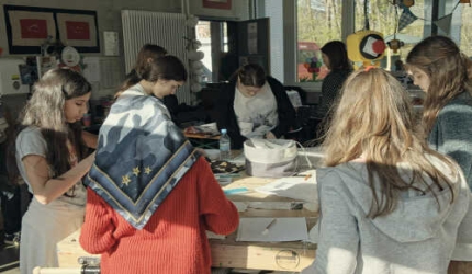 Schülerinnen arbeiten stehend am Tisch an einem Projekt