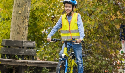 Junge auf Fahrrad auf dem laubbedecktem Schulgelände