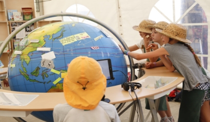 Vier Kinder bekleben eine übergroße Weltkugel