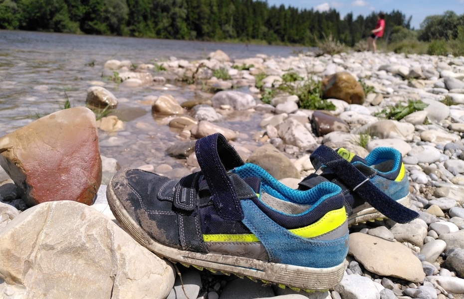 Ein Paar Kinderturnschuhe am Isarufer